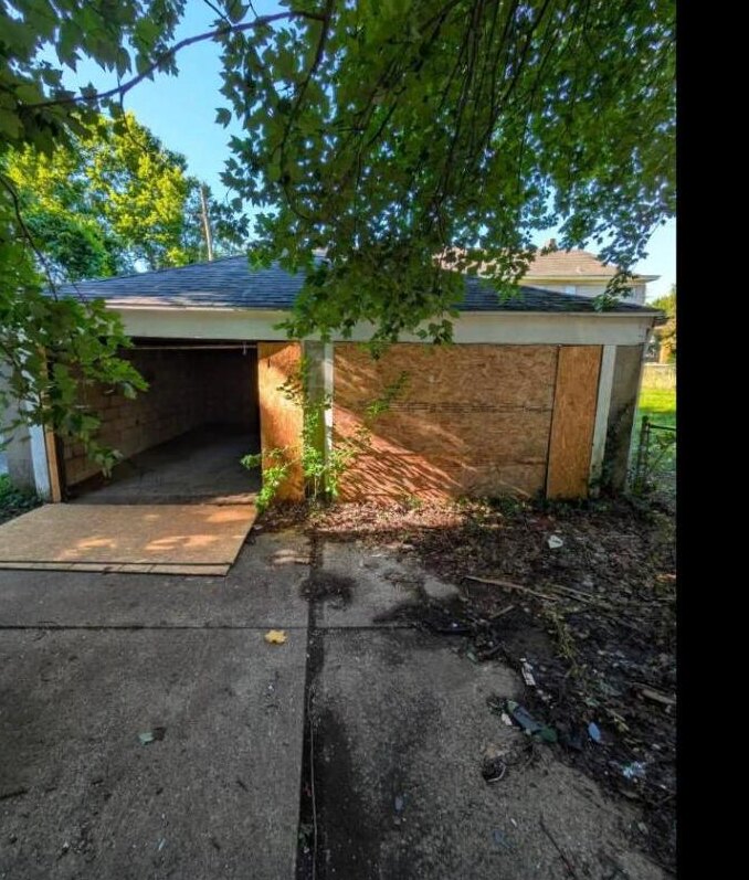 Weathered, boarded-up two-car garage before repair