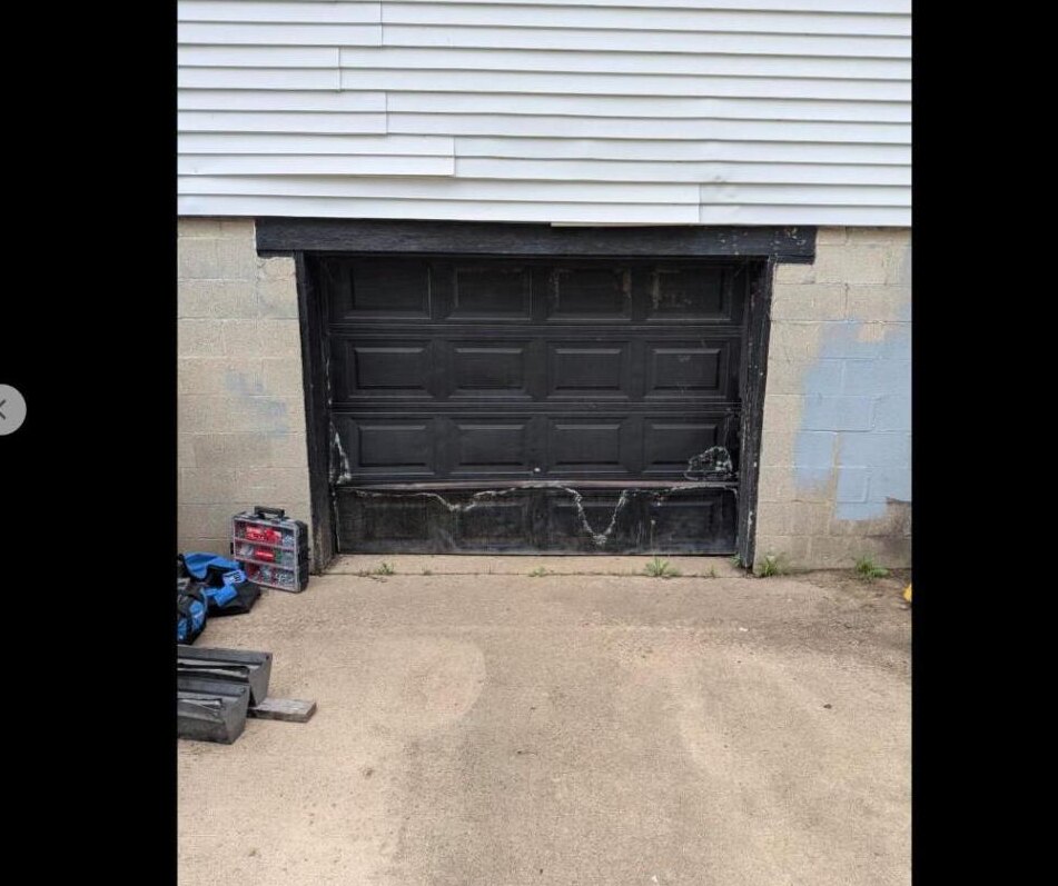 Worn garage door before professional repair in Dayton