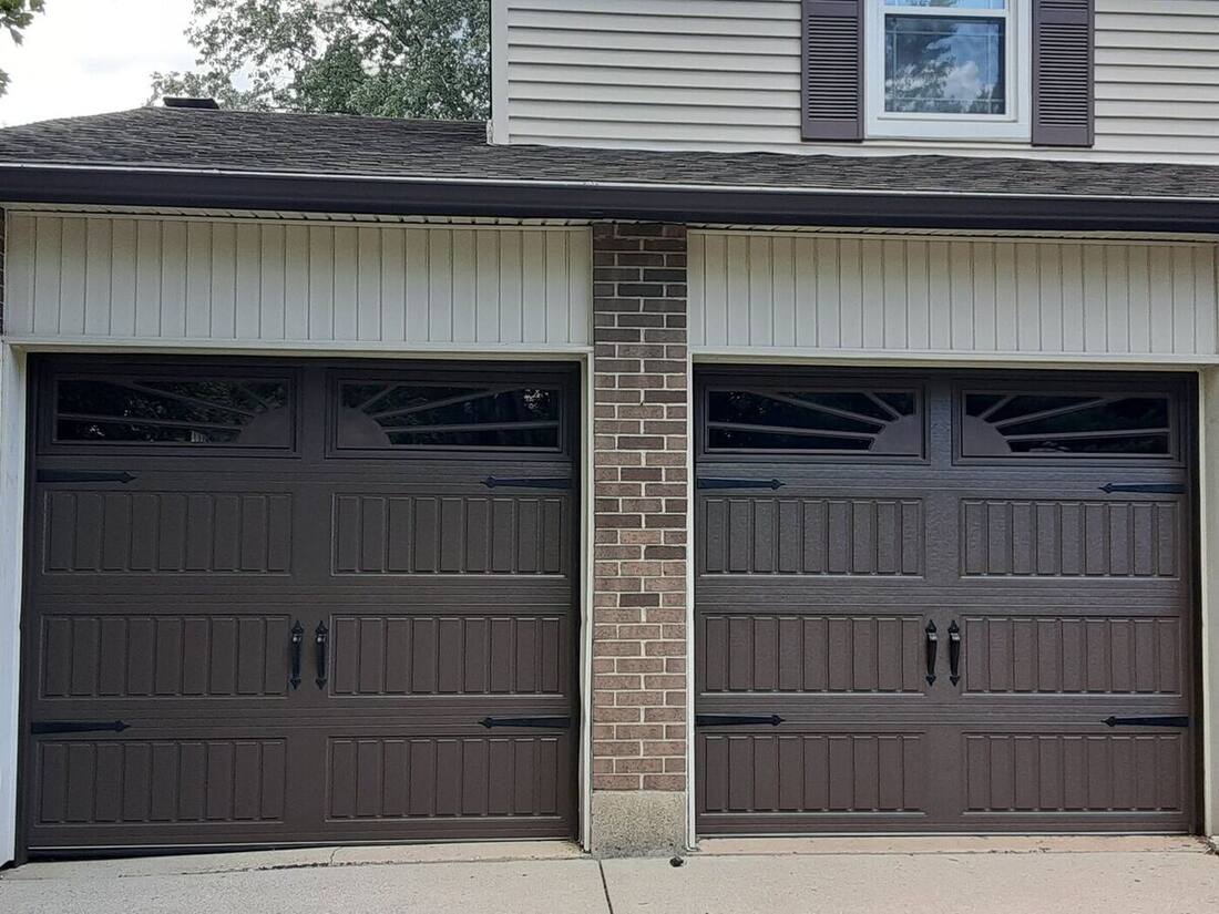 New brown carriage-style garage doors with decorative windows