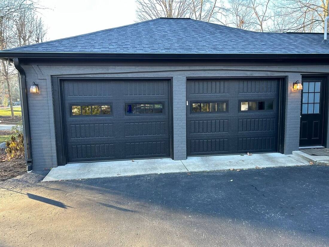 New black double garage doors installed on a modern home